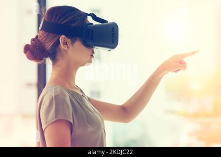 The possibilities are endless. a young businesswoman wearing a VR headset while connecting to a user interface in an office. Stock Photo