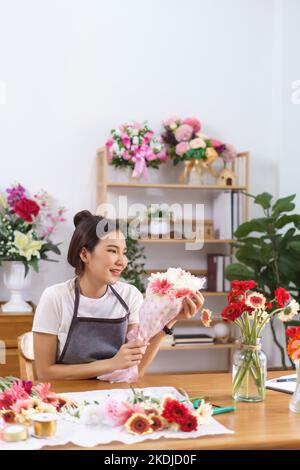 Flower shop concept, Female florist smile and holds colorful flower bouquet with paper and ribbon. Stock Photo