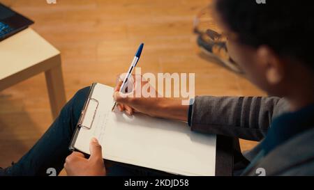 Psychology counselor taking notes on clipboard at therapy session, listening to man having relationship problems. Giving marriage counseling to help married person in office. Close up. Stock Photo