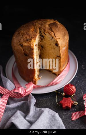 Panettone Christmas Cake. Italian sweet bread on plate on the dark table. Stock Photo