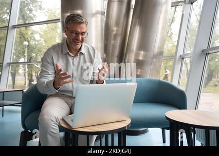 Middle-aged man in glasses communicates online with a subordinate Stock Photo
