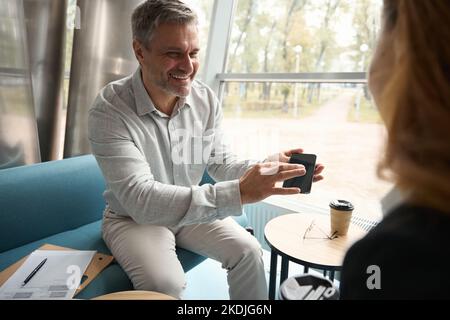 Man with smile shows video on phone to female colleague Stock Photo