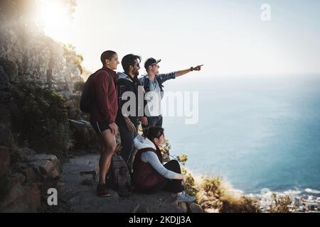 What is that. a young man pointing something out to his friends while on a mountain hike. Stock Photo