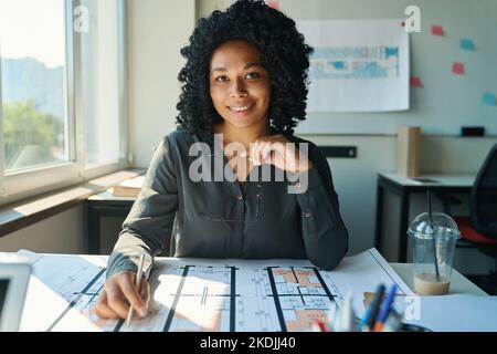 African american female designer sitting in front house floor plan Stock Photo