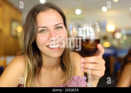 Happy teen holding soda cup toasting with tou in a restaurant Stock Photo