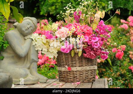 Bouquet of Sweet Peas , Crops honesty (Lunaria annua), Hydrangea (Hydrangea sp), Rose (Rosa sp), Aster 'Aster sp), Zen spirit statue, in the garden Stock Photo