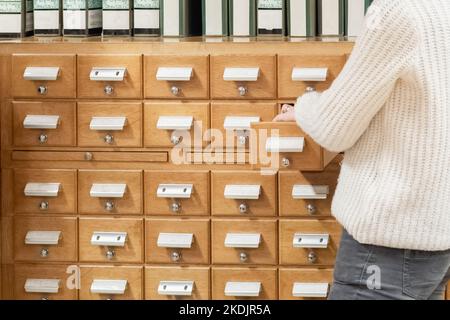Librarian hand opens library card or file catalog box. Stock Photo
