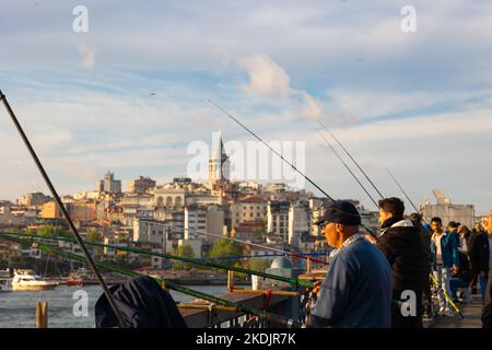 Citizens of Istanbul. Local people fishing with fishing rods on Galata Bridge. Istanbul view at sunset. Istanbul Turkey - 5.7.2022 Stock Photo