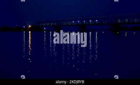 night, in the water the bridge and its lights are reflected. A long bridge over the river. High quality photo Stock Photo