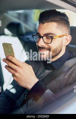 He gets things done even on the go. a young designer using a cellphone in a car. Stock Photo