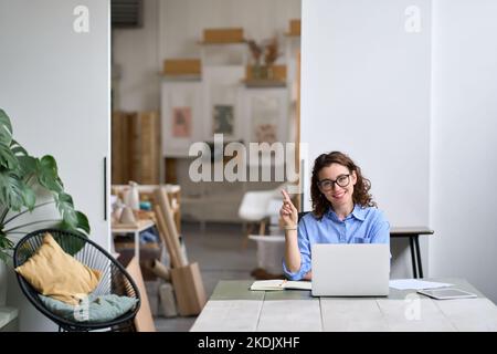 Young happy business woman or student working on laptop pointing aside. Stock Photo