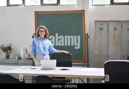 Young happy business woman coach or teacher standing at desk in office. Stock Photo