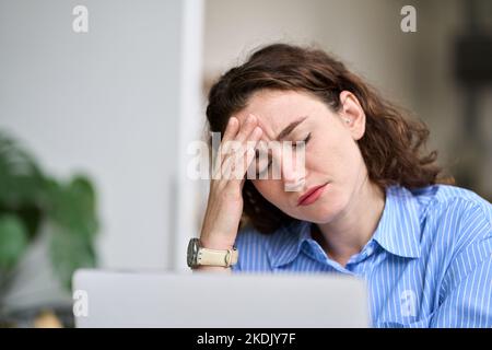 Tired young business woman touching head feeling headache fatigue at work. Stock Photo