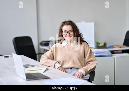 Young happy professional business woman sitting at work desk, portrait. Stock Photo