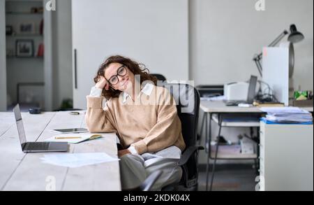 Young happy relaxed professional business woman sitting at work desk, portrait. Stock Photo