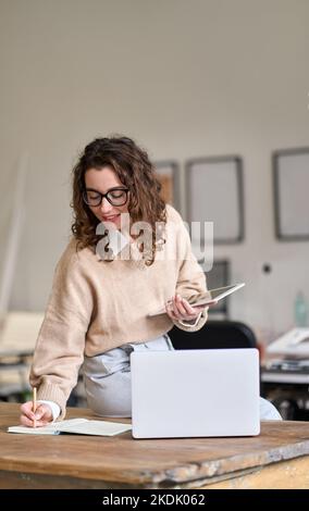 Young smiling business woman working in office using digital tablet. Vertical Stock Photo
