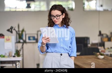 Young smart busy professional business woman using digital tablet in office. Stock Photo