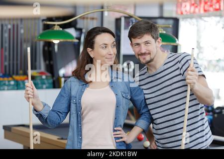 young couple playing snooker together in bar Stock Photo