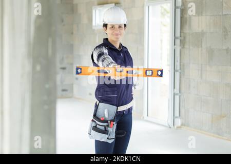 female builder using spirit level indoors Stock Photo