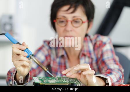 young female tech or engineer repairs electronic equipment Stock Photo