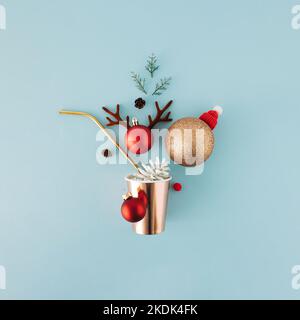 Christmas greeting concept with paper drinking glass, straw and ornaments on blue background. Stock Photo