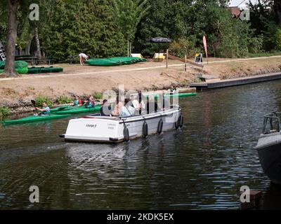 Lokeren, Belgium, August 27, 2022, friends and family sail a pleasure boat and pass a dock for canoes on the river Durme in Lokeren Stock Photo