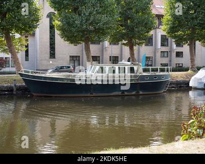Old weathered boat is moored on the river Durme in Lokeren, Belgium Stock Photo