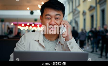Man talking on phone looking at laptop screen male tourist client making order in online store remotely booking ticket on Internet businessman Stock Photo
