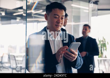 Asian businessman is using phone during break time in modern office Stock Photo
