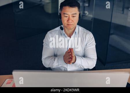Asian businessman in headphones working on computer in modern coworking Stock Photo
