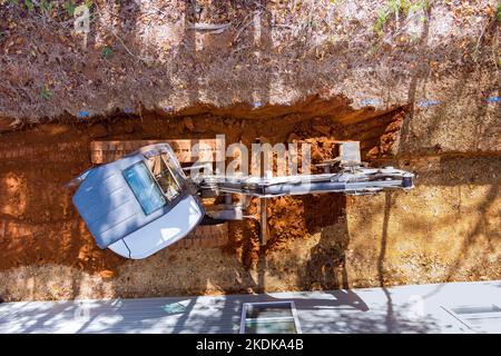 An earthmoving worker digging ground at construction site with crawler excavator bucket used for earthmoving work Stock Photo