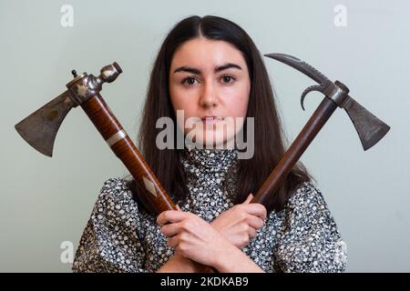 London, UK.  7 November 2022. A staff member with (L) ‘A very rare and fine North American pipe tomahawk’, late 18th century, (Est. £8,000 - £10,000) and ‘A rare North American tomahawk’, late 18th century, (Est. £3,000 - £4,000) at a photocall of Bonhams Arms and Armour sale which includes the Chris Wynn collection of early Purdeys. The auction will take place at Bonhams Knightsbridge on 9 November.  Credit: Stephen Chung / Alamy Live News Stock Photo