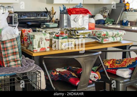 Christmas presents on an island in a cluttered kitchen. Stock Photo