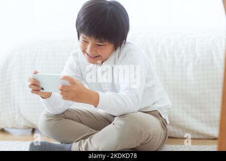 Japanese kid using smartphone at home Stock Photo