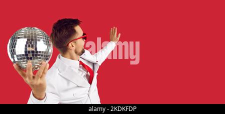 Happy man holding disco ball and dancing isolated on red copy space banner background Stock Photo