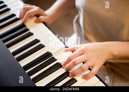 An adult woman plays an electric piano, hands close-up. Female hands on the keys of a portable electronic piano Stock Photo