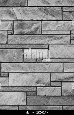 Solid brick wall created with natural stone bricks in a random pattern with layers in a black and white monochrome. Stock Photo