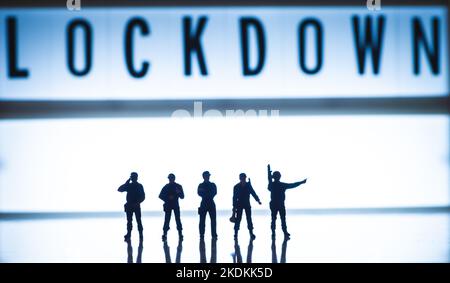 Lockdown concept images - Low key blue tint miniature toy figures of security forces - silhouette of army or police forces. Stock Photo