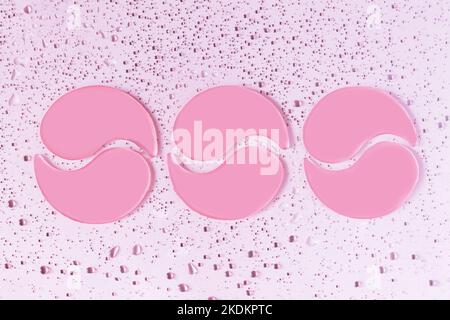 Three pair of pink hydrogel collagen eye patches on light background with drops. Beauty, cosmetics for skin care, lifting, wrinkle removal concept Stock Photo