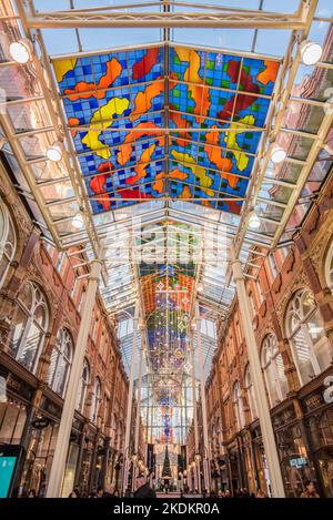 Arcade in the Victoria Quarter, Leeds,Yorkshire  with brightly coloured abstract pattern canopy in blue,yellow, red and green,designed by Brian Clark Stock Photo