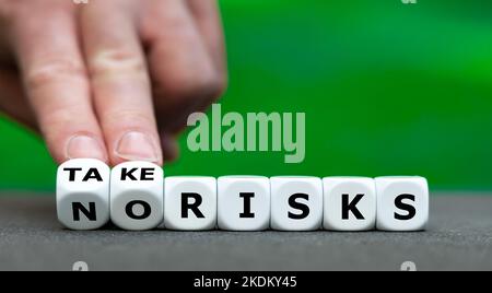 Hand turns dice and changes the expression 'no risks' to 'take risks'. Stock Photo