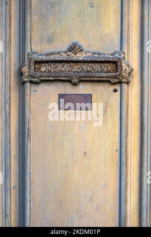 Old weathered wooden door with antique decorated rusty mailbox for letters and news (in czech: dopisy a noviny) and blank metal name label Stock Photo