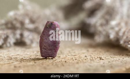 Rough Uncut Pinkish Ruby Stone on Wooden Background, Ruby is traditional popular gemstone for jewelry Stock Photo