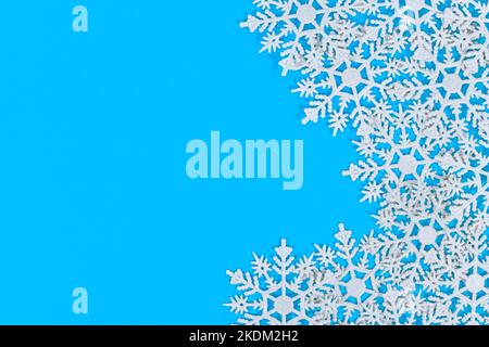 White Snowflake Christmas tree ornaments on side of blue background with copy space Stock Photo