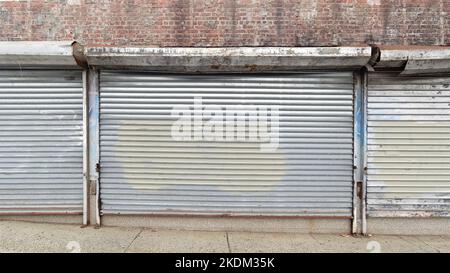Plain steel roller window shutters with paint on a closed brick building in the Bronx. Blank for mock up or advertisement use Stock Photo