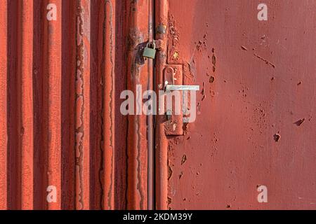 Old rusty iron gate with vintage door handle and locked padlock Stock Photo