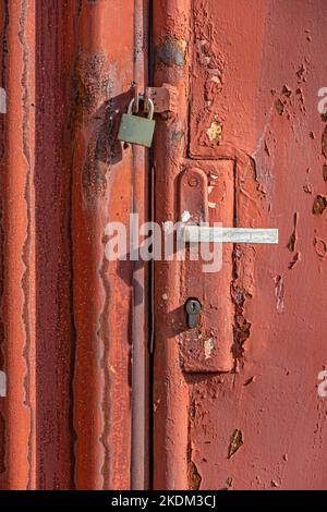 Old rusty iron gate with vintage door handle and locked padlock Stock Photo