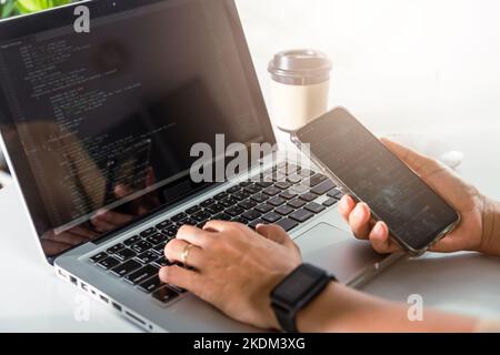 Programmer woman looking mobile phone program code at workplace Stock Photo