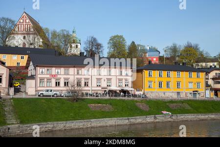 Porvoo, Finland - May 7, 2016: Colorful wooden houses stand along the river coast in old Porvoo town, ordinary people walk the street Stock Photo