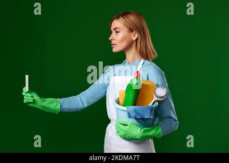 woman with bucket with cleaning supplies showing empty card Stock Photo